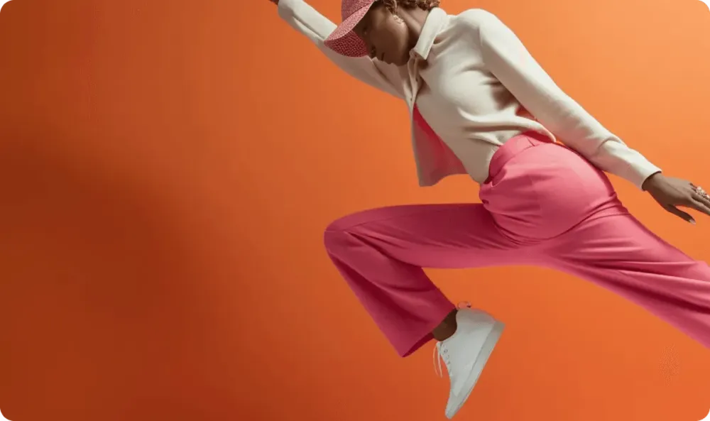 Model maakt een dynamische sprong in de lucht tegen een oranje achtergrond, symbool voor een snelle Lightspeed naar Shopify migratie door e-commerce bureau Opklopper.